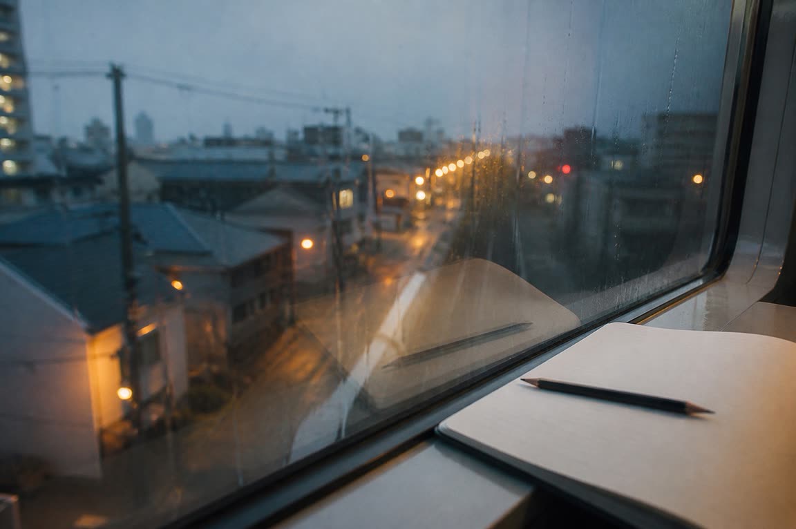 雨の窓ごしに、暮れかけた街が見える机の上